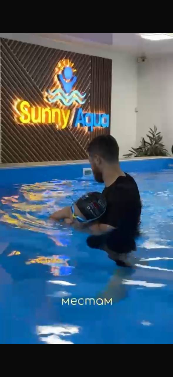 Инструктор поддерживает ребёнка во время занятия в бассейне Sunny Aqua